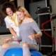 teenage girl on blue excercise ball balancing with assistance of nurse