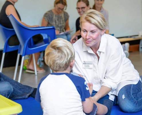woman in lab coat smiling at child with parents around them in a excercise room