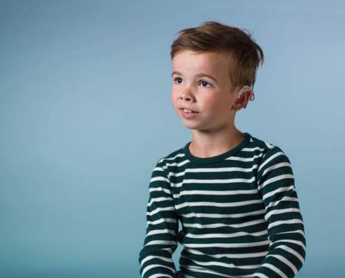 young deaf boy in front of blue background
