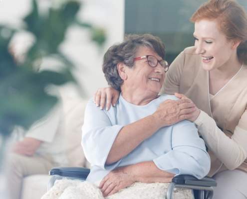 elderly woman in chair and nurse smiling at each other