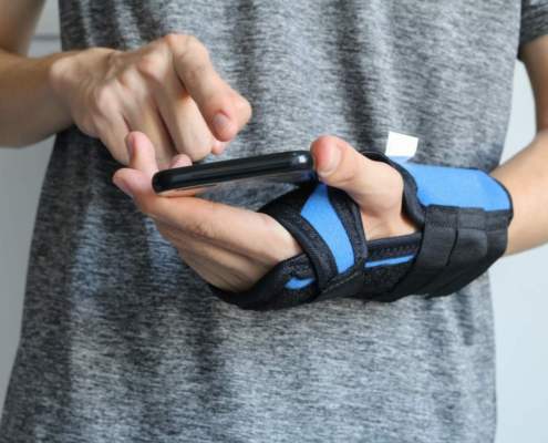 person scrolling on phone with hand rehabilitation glove